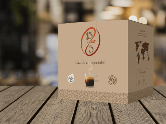 Confezione di cialde di caffè compostabili 15zero5 con tazzina di caffè fumante su tavolo di legno